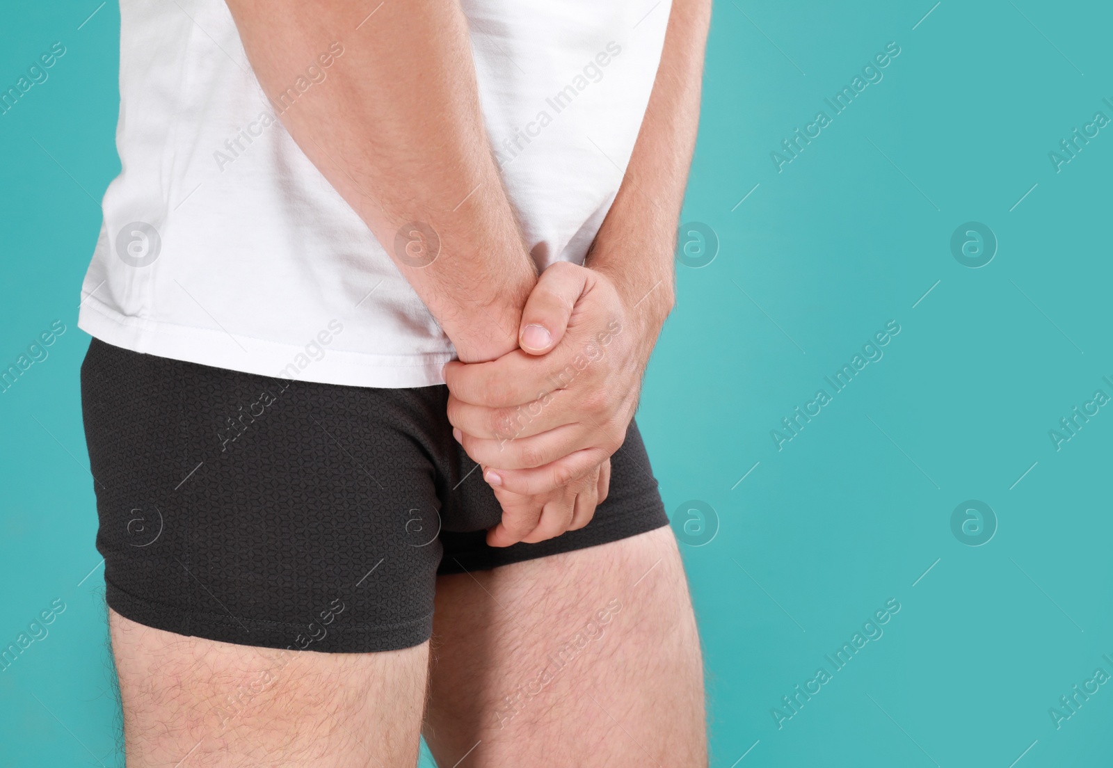 Photo of Man suffering from pain on turquoise background, closeup. Urology problems