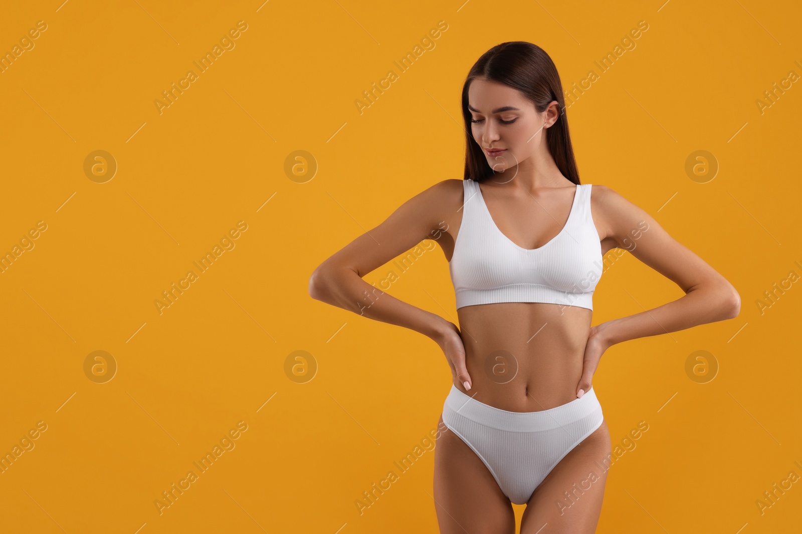 Photo of Young woman in stylish white bikini on orange background. Space for text