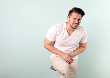Photo of Young man with urological problems suffering from pain on color background