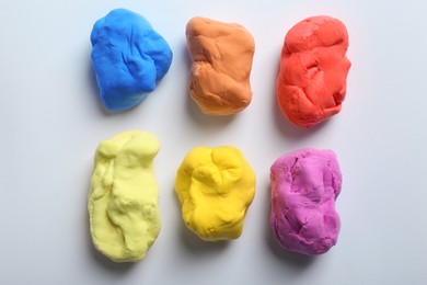 Different color play dough on white background, top view