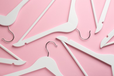 Photo of White hangers on pink background, flat lay