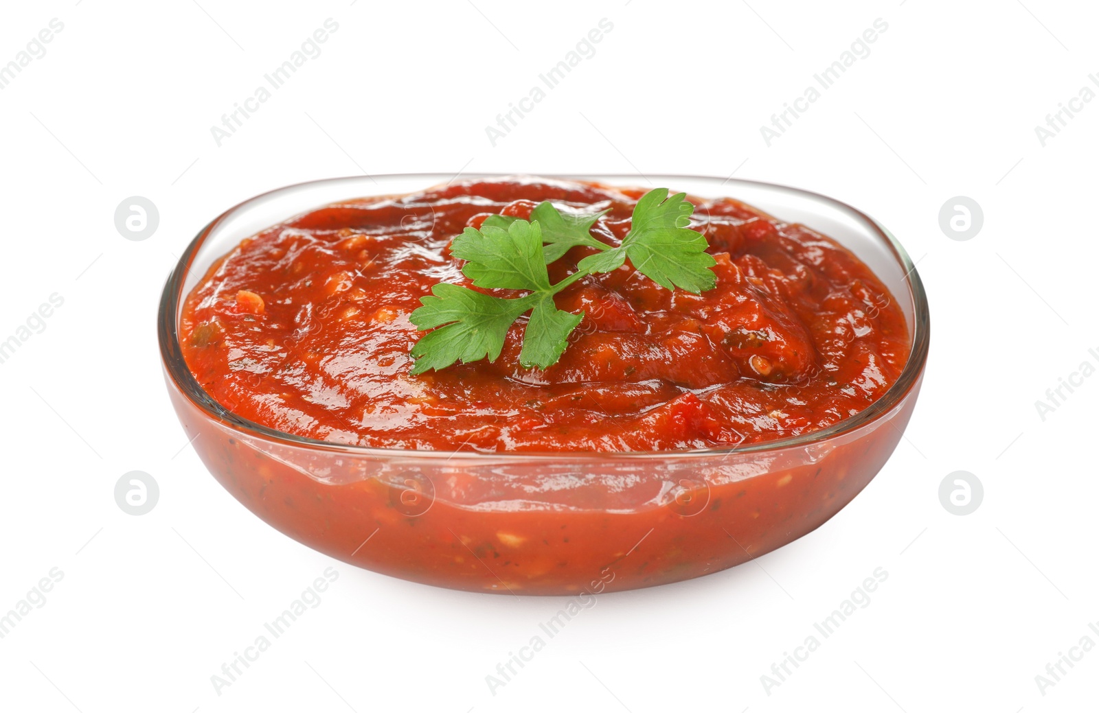 Photo of Delicious adjika sauce and parsley in glass bowl isolated on white