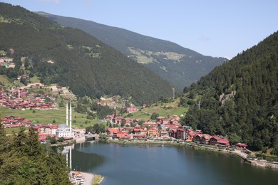 Photo of Buildings under mountains near lake on sunny day