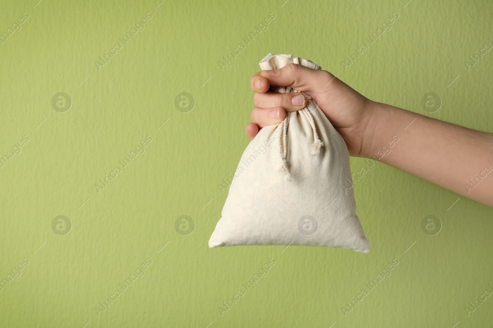 Photo of Woman holding full cotton eco bag on light green background, closeup