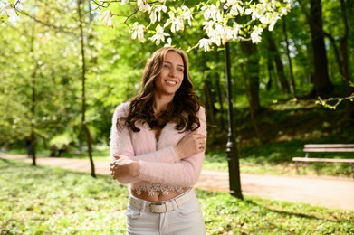 Beautiful young woman near blossoming tree on spring day