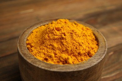 Photo of Aromatic saffron powder in bowl on wooden table, closeup