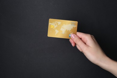 Woman holding credit card on black background, closeup