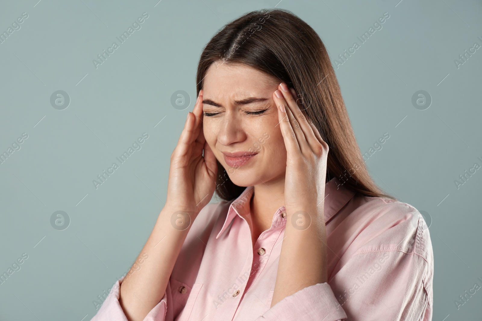 Photo of Young woman suffering from migraine on grey background