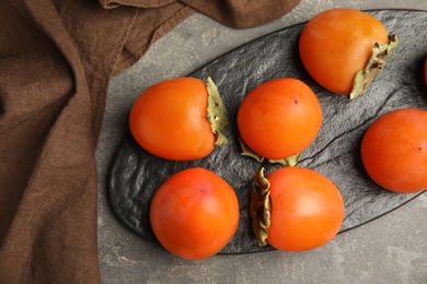 Photo of Tasty ripe persimmons on grey table, flat lay