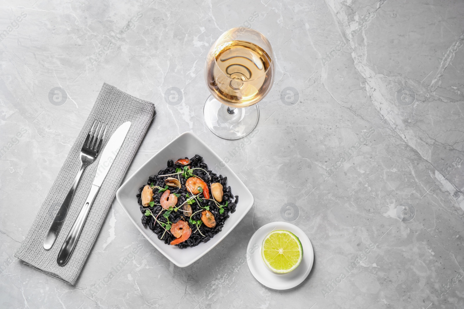 Photo of Delicious black risotto with seafood served on light grey marble table. Space for text