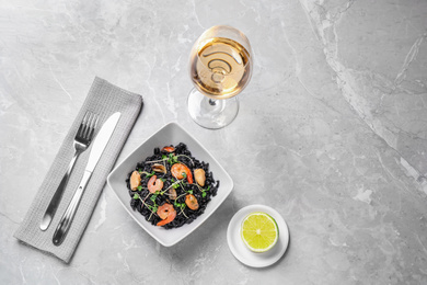 Photo of Delicious black risotto with seafood served on light grey marble table. Space for text