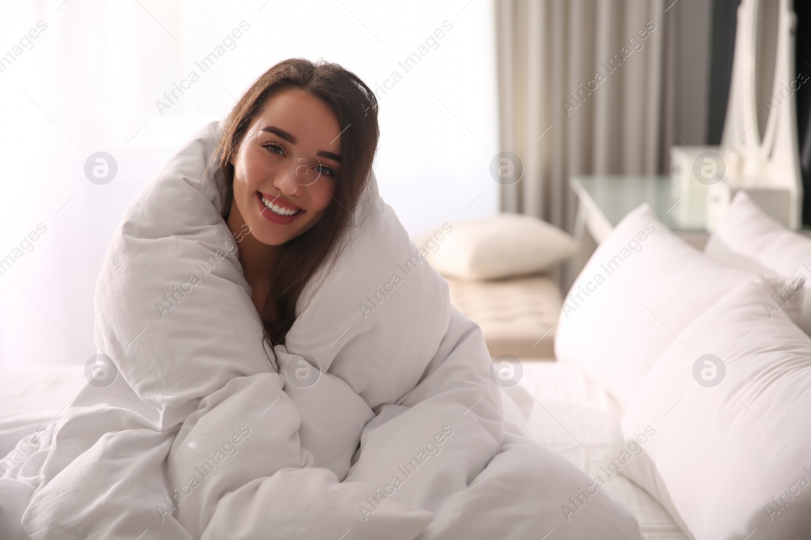 Photo of Beautiful young woman wrapped with soft blanket on bed at home