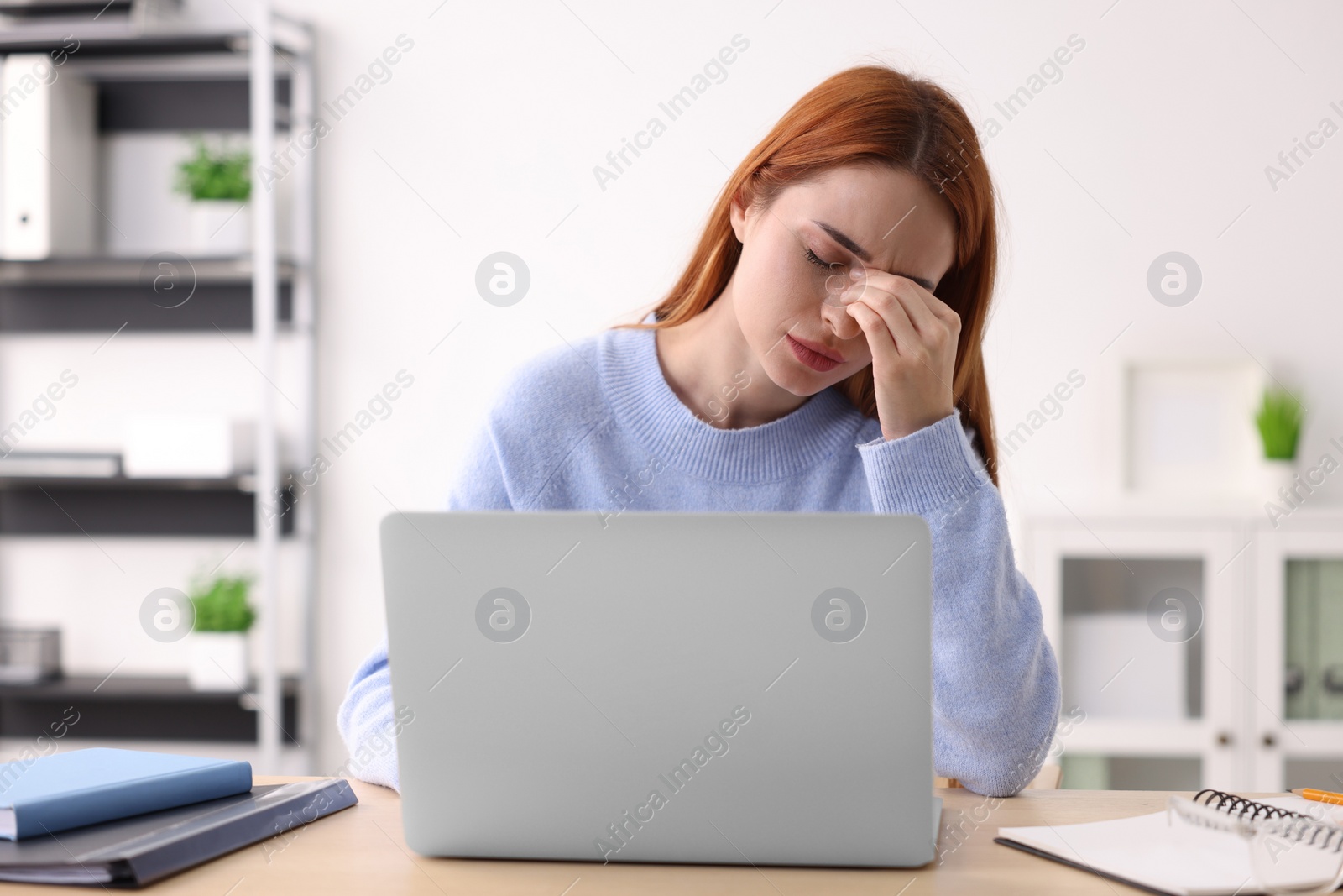 Photo of Woman suffering from headache at workplace in office