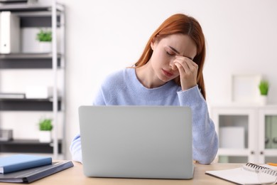 Woman suffering from headache at workplace in office