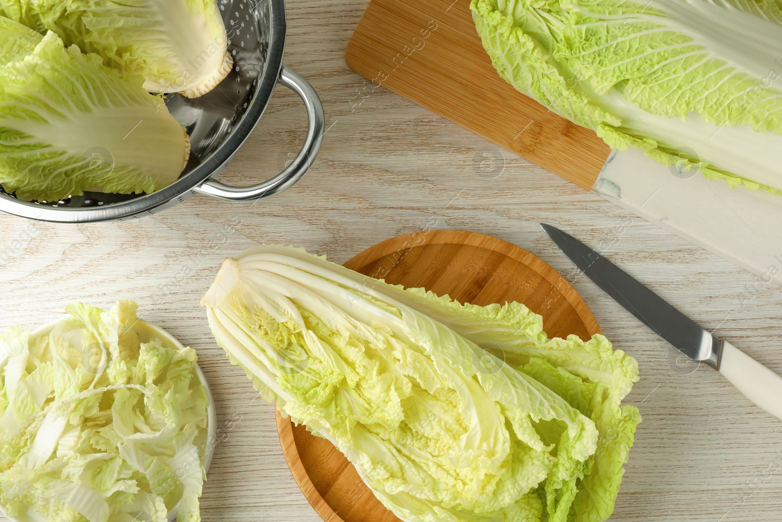 Photo of Whole and cut fresh ripe Chinese cabbages on white wooden table, flat lay