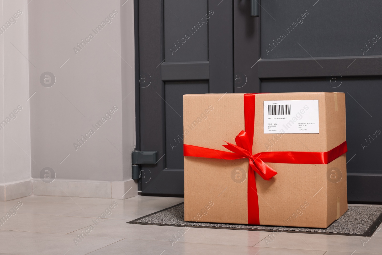 Photo of Christmas gift box on floor near door, space for text. Sending present by mail