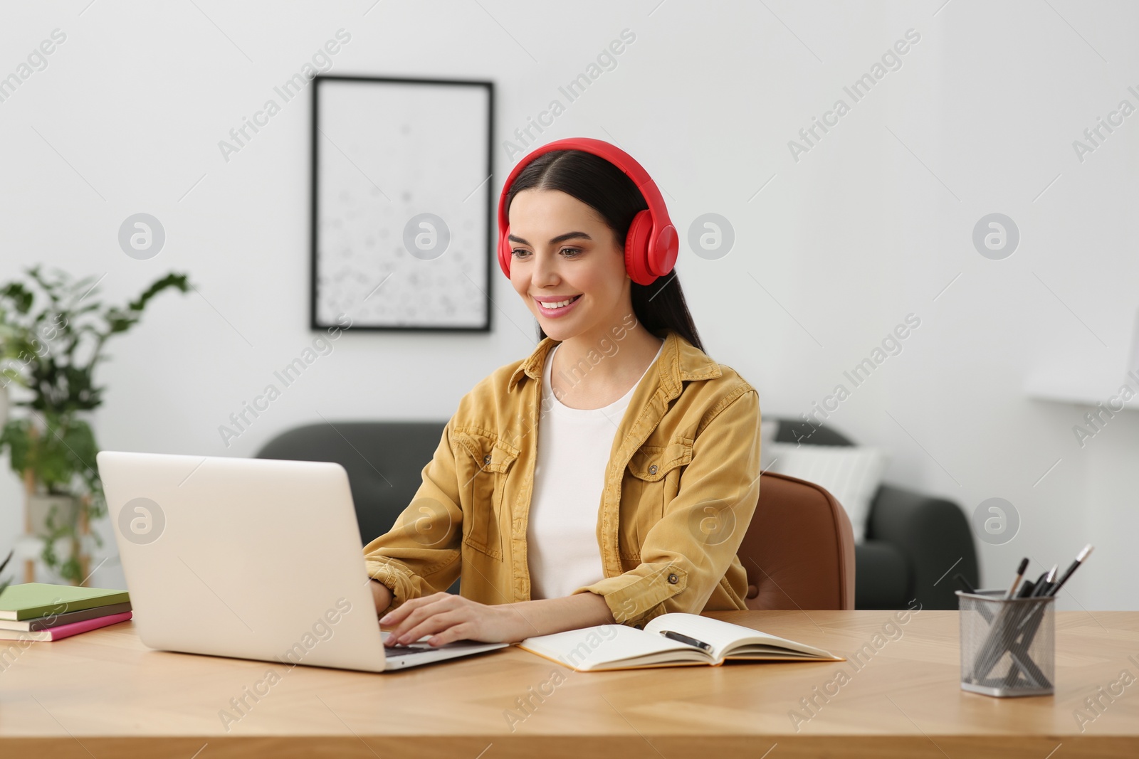 Photo of Online translation course. Student in headphones typing on laptop at home