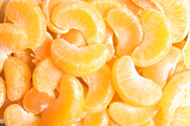 Pieces of ripe tangerines as background, top view