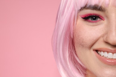 Photo of Smiling woman with bright makeup and fake freckles on pink background, closeup. Space for text