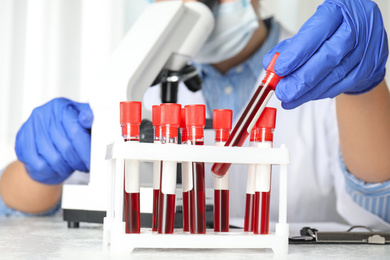 Photo of Scientist taking test tube with blood sample from rack in laboratory, closeup. Virus research