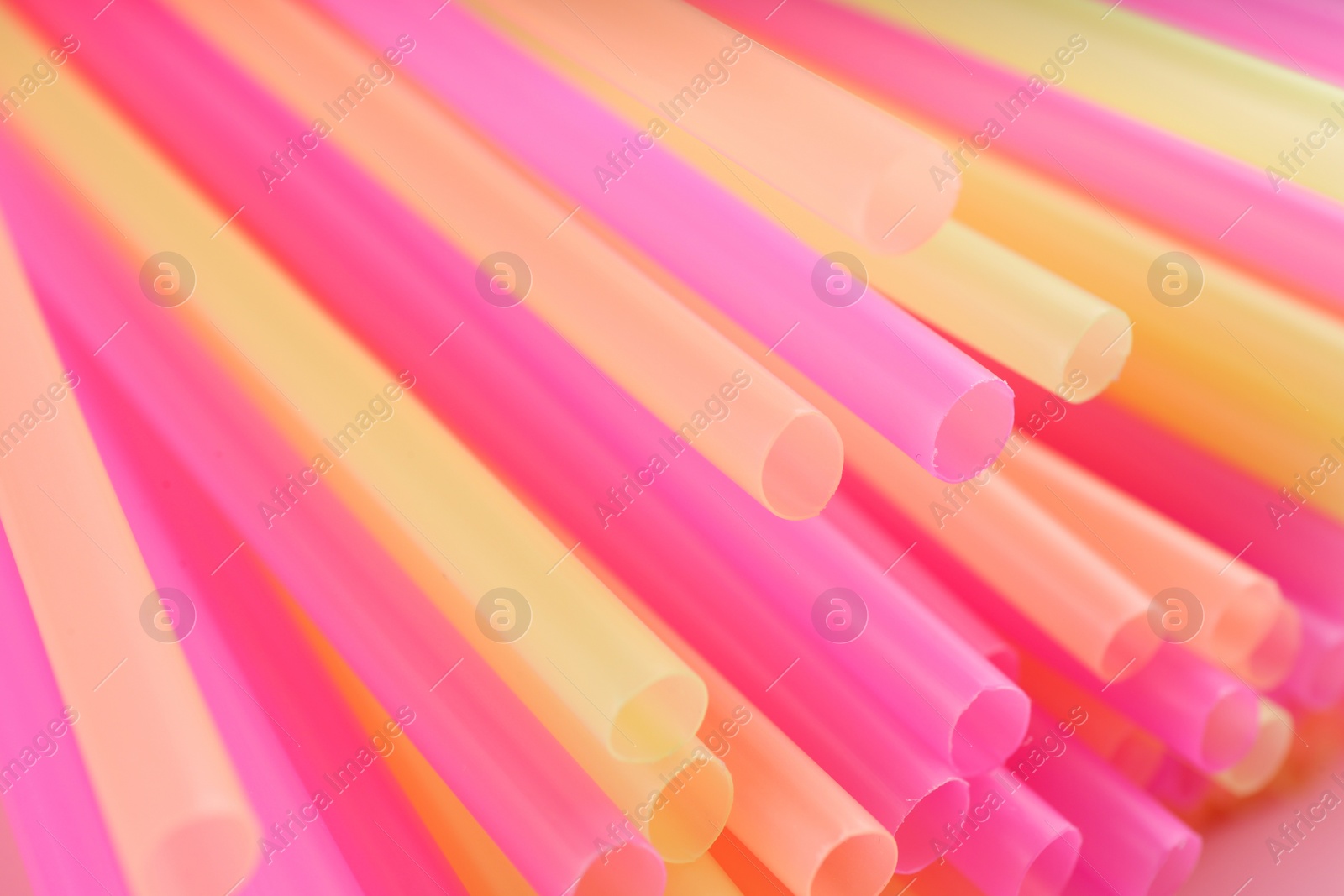 Photo of Heap of colorful plastic straws for drinks as background, closeup