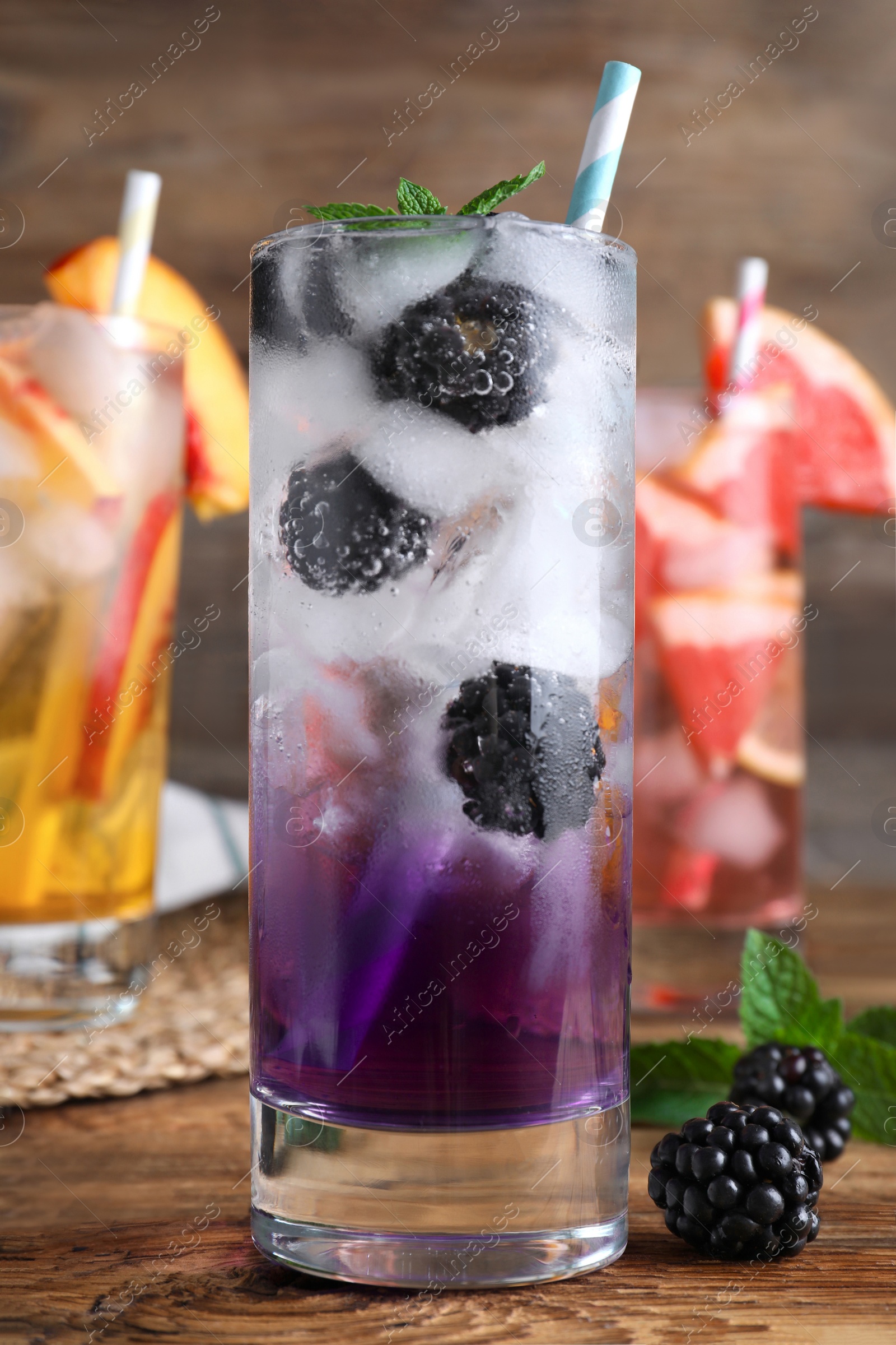 Photo of Delicious blackberry lemonade made with soda water on wooden table