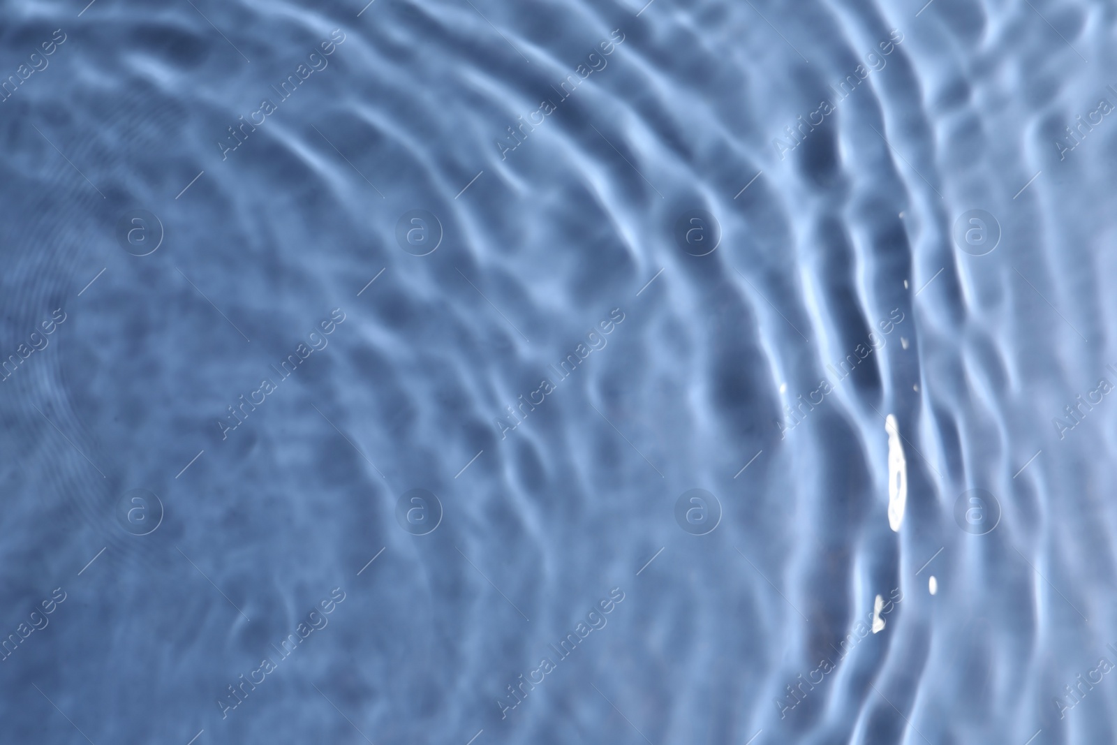 Photo of Closeup view of water with rippled surface on blue background