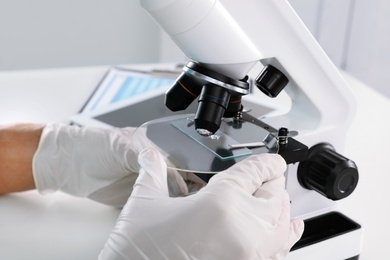 Photo of Doctor using microscope at table, closeup. Medical object