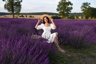 Beautiful young woman sitting in lavender field