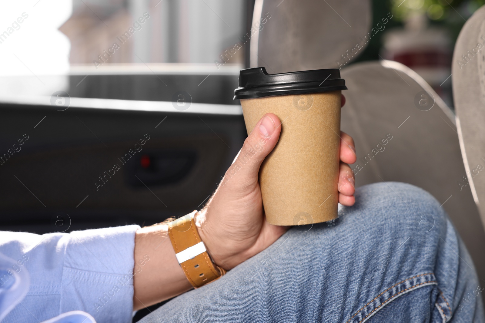 Photo of Coffee to go. Man with paper cup of drink in car, closeup