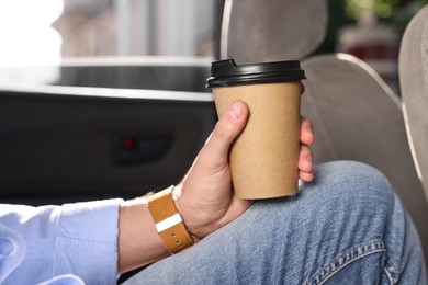 Photo of Coffee to go. Man with paper cup of drink in car, closeup