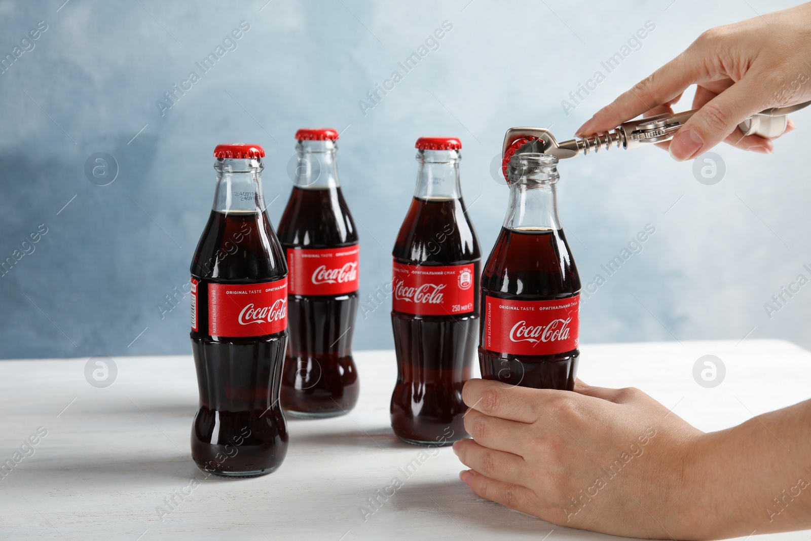 Photo of MYKOLAIV, UKRAINE - NOVEMBER 15, 2018: Woman opening bottle of Coca Cola at table, closeup