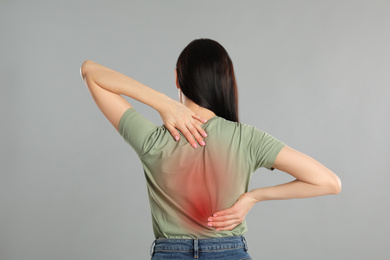 Image of Woman suffering from pain in back on light grey background