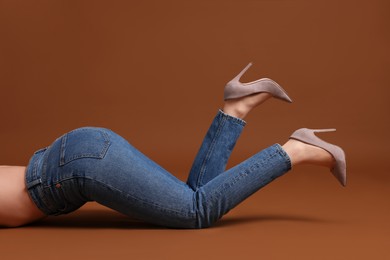 Photo of Woman in stylish jeans on brown background, closeup