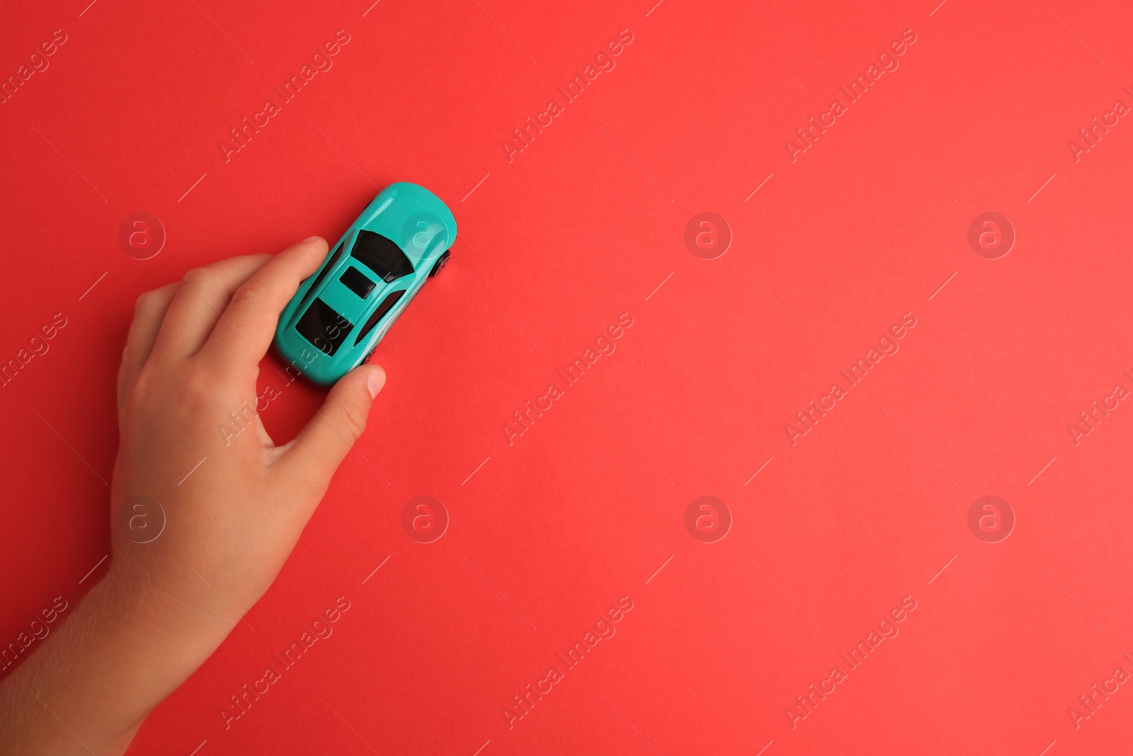 Photo of Child playing with toy car on red background, top view. Space for text