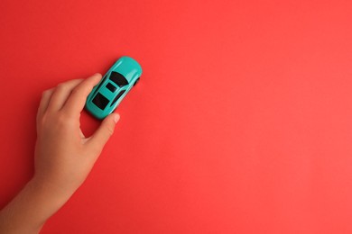 Photo of Child playing with toy car on red background, top view. Space for text