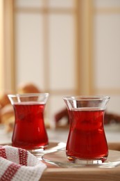 Glasses of traditional Turkish tea on wooden tray indoors