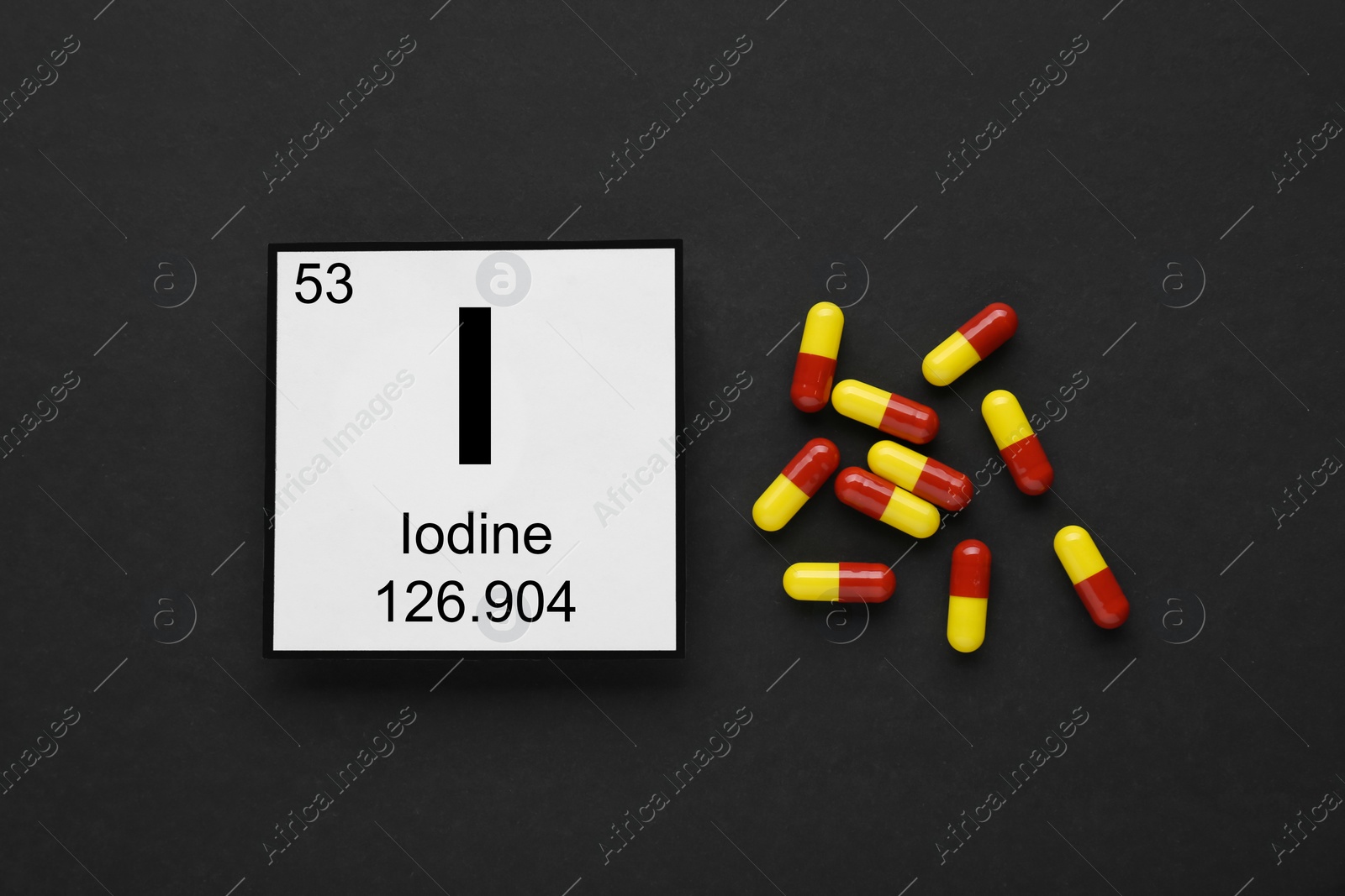 Photo of Card with iodine element and pills on black background, flat lay