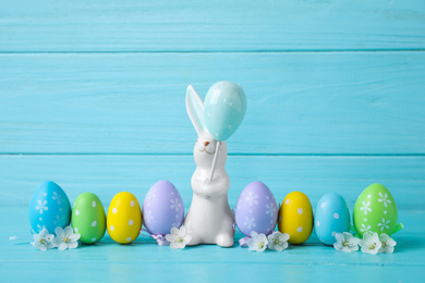 Easter bunny and painted eggs on light blue wooden background