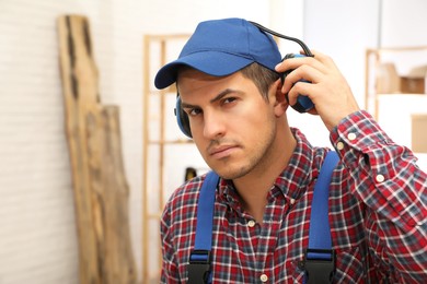 Worker wearing safety headphones indoors, space for text. Hearing protection device