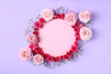 Photo of Frame made with fresh flowers and blank card on color background, top view