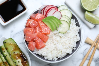 Delicious poke bowl with salmon and vegetables served on white marble table, flat lay