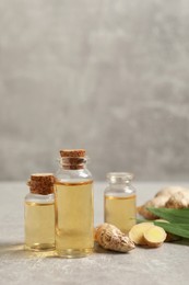 Photo of Ginger essential oil in bottles on light grey marble table