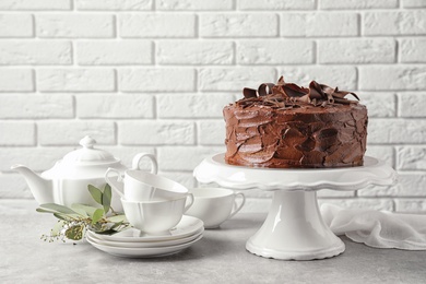 Stand with tasty homemade chocolate cake and tea set on table