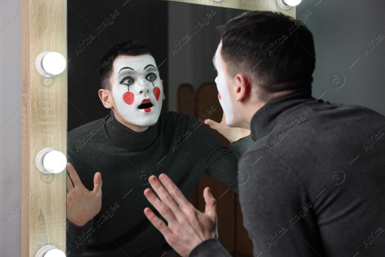 Photo of Mime artist posing near mirror in dressing room