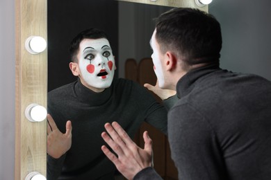 Photo of Mime artist posing near mirror in dressing room