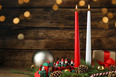 Photo of Burning candles and festive decor on wooden table, space for text. Christmas eve