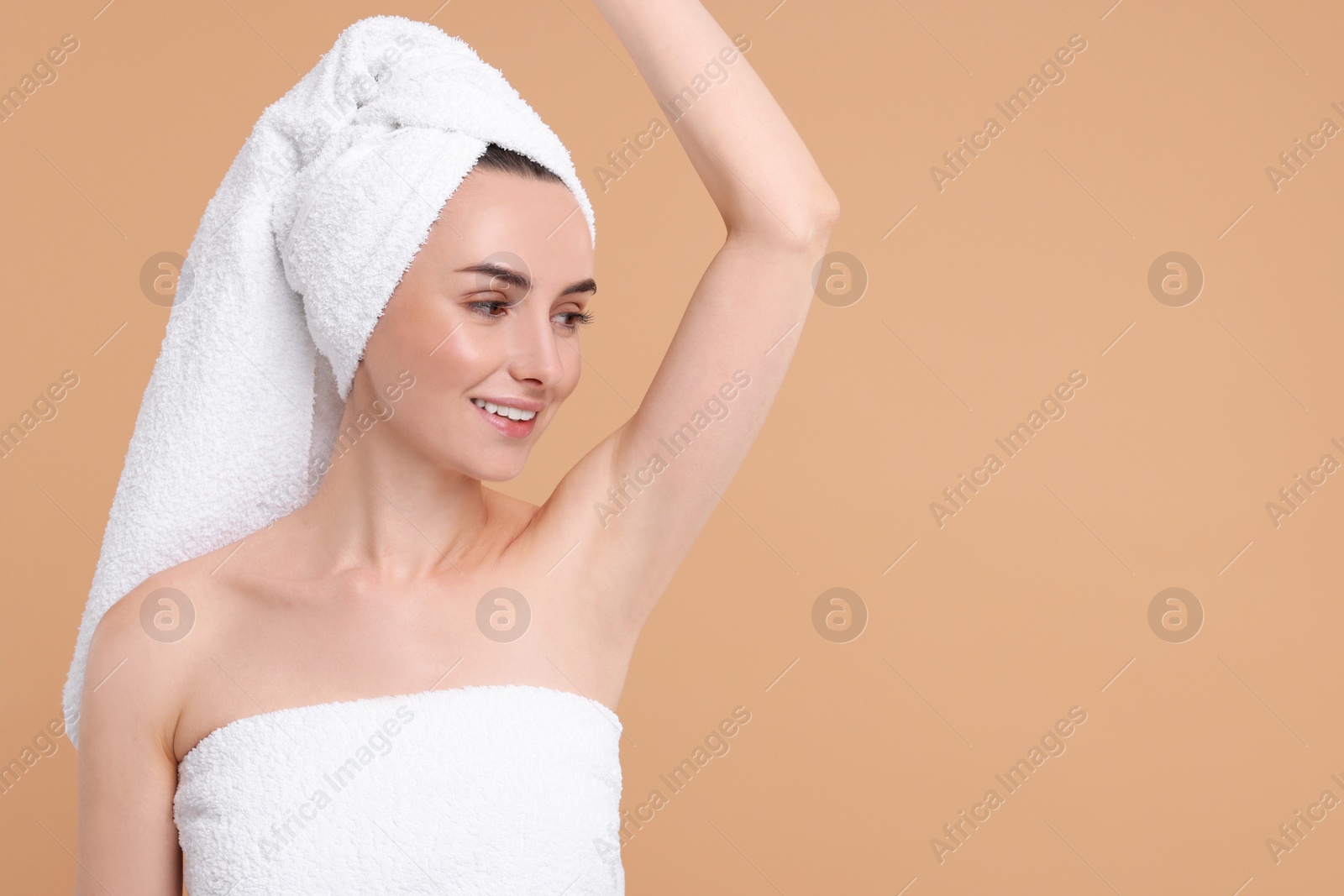 Photo of Beautiful woman showing armpit with smooth clean skin on beige background, space for text