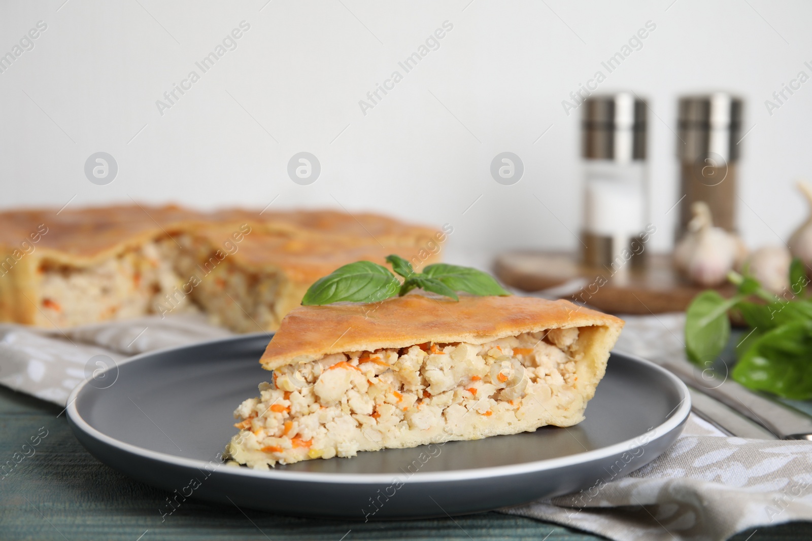 Photo of Slice of delicious meat pie with basil on blue wooden table, space for text