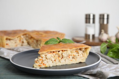 Photo of Slice of delicious meat pie with basil on blue wooden table, space for text